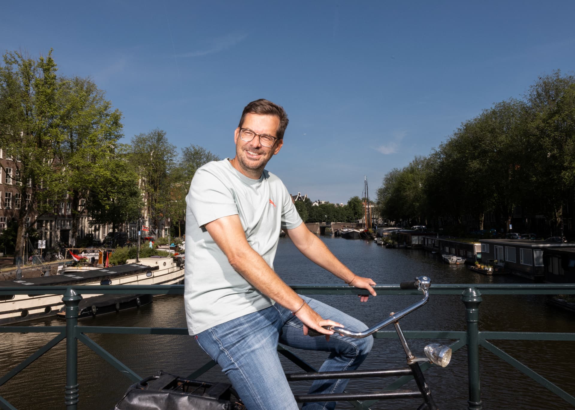 Dennis Gerrits sitting on his bicycle on an Amsterdam bridge